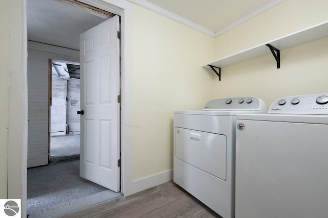 laundry room featuring laundry area, ornamental molding, baseboards, washer and dryer, and light wood-style flooring