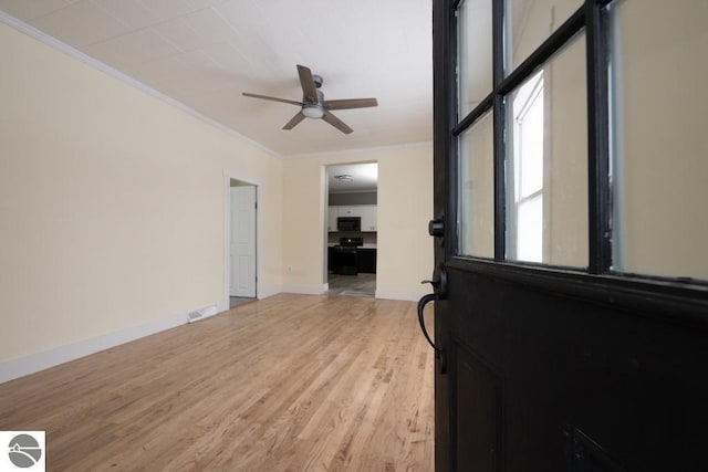 interior space featuring a ceiling fan, crown molding, light wood finished floors, baseboards, and visible vents