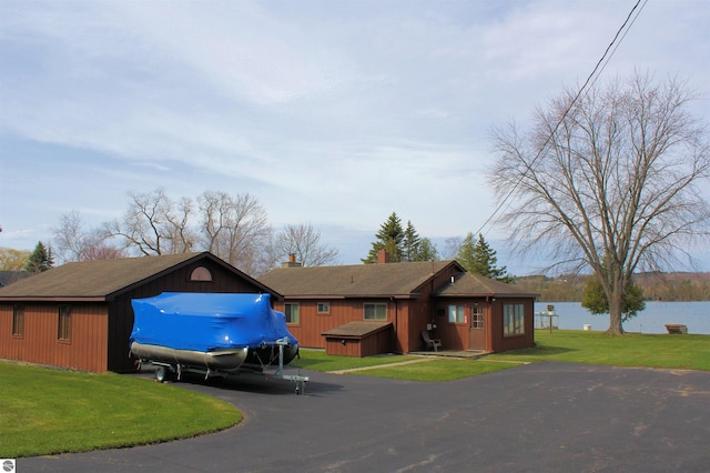view of front facade with aphalt driveway, a front yard, and a water view