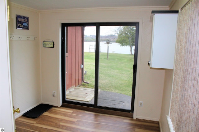 doorway with ornamental molding, a water view, wood finished floors, and baseboards