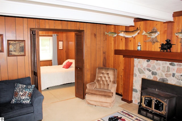 living area with beam ceiling, wooden walls, tile patterned flooring, and a wood stove