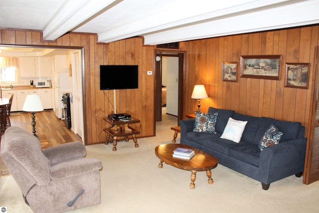 living area with wood walls, beamed ceiling, and carpet floors