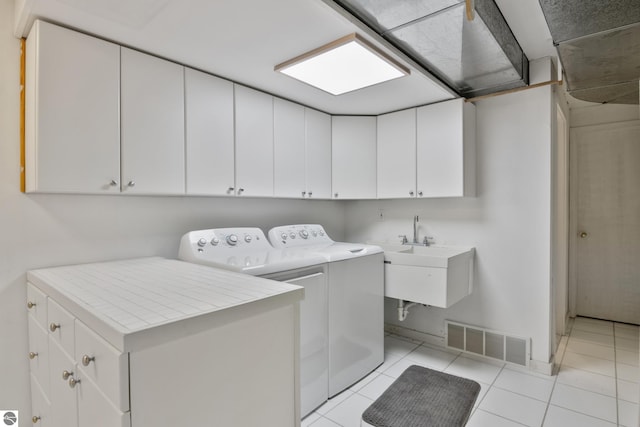 1995 San Marino Trl, Kewadin, MI 49648 - clothes washing area featuring cabinet space, a sink, washer and clothes dryer, visible vents, and light tile patterned flooring