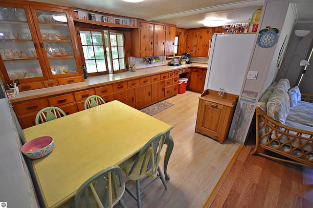 1900 Pavilion Dr, Lake City, MI 49651 - kitchen featuring glass insert cabinets, light countertops, brown cabinets, and light wood-type flooring
