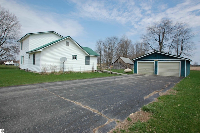 5525 S Mccauley Rd, Alger, MI 48610 - view of side of home featuring a lawn, a detached garage, and an outbuilding