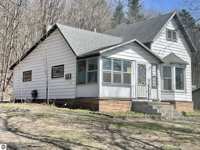 10978 Platte St, Honor, MI 49640 - view of front of property featuring roof with shingles and a sunroom