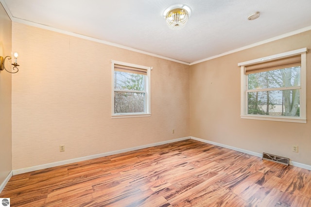 7888 E Broomfield Rd, Mount Pleasant, MI 48858 - spare room featuring wood finished floors, a healthy amount of sunlight, crown molding, and visible vents
