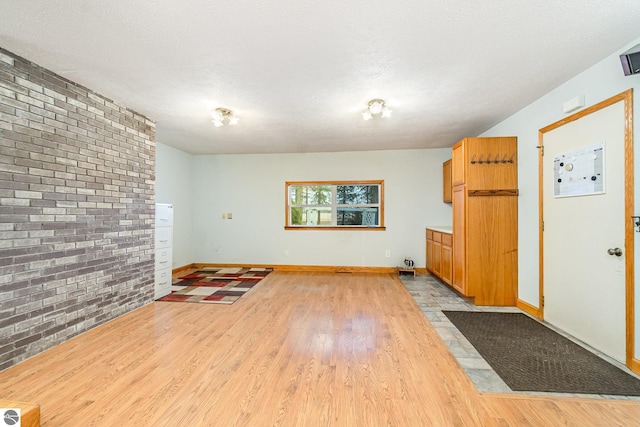 7888 E Broomfield Rd, Mount Pleasant, MI 48858 - interior space featuring a textured ceiling, wood finished floors, brick wall, and baseboards