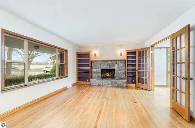 7888 E Broomfield Rd, Mount Pleasant, MI 48858 - unfurnished living room featuring hardwood / wood-style flooring, baseboards, french doors, and a fireplace