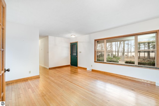 7888 E Broomfield Rd, Mount Pleasant, MI 48858 - empty room with baseboards, visible vents, and light wood-style flooring