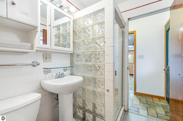 7888 E Broomfield Rd, Mount Pleasant, MI 48858 - full bath with a shower stall, stone finish flooring, toilet, tile walls, and backsplash