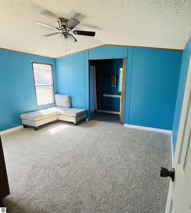 unfurnished room with vaulted ceiling, carpet flooring, baseboards, a ceiling fan, and a textured ceiling