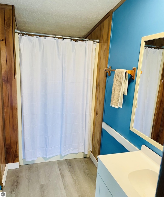 bathroom with vanity, a textured ceiling, shower / tub combo with curtain, and wood finished floors