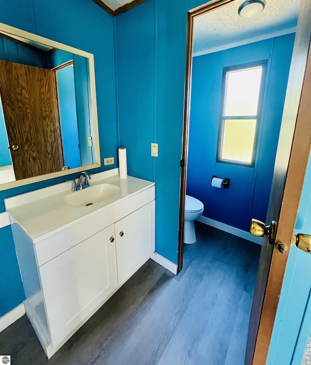 bathroom featuring vanity, toilet, baseboards, a textured ceiling, and wood finished floors