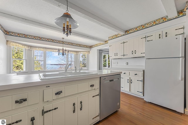 kitchen featuring beamed ceiling, a sink, a healthy amount of sunlight, dishwasher, and freestanding refrigerator
