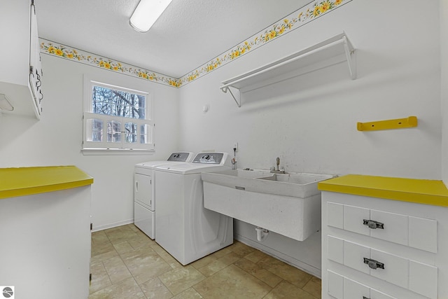 washroom with baseboards, stone finish flooring, washer and clothes dryer, and a sink