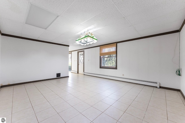 empty room featuring baseboards, ornamental molding, a baseboard heating unit, and a drop ceiling