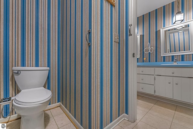 bathroom featuring wallpapered walls, baseboards, toilet, tile patterned floors, and vanity