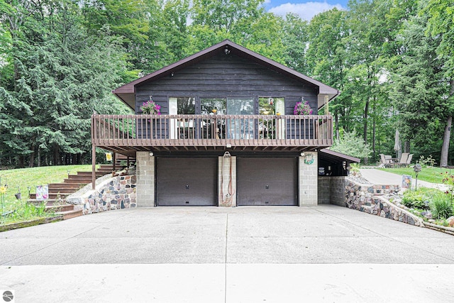view of front of property with a deck, concrete driveway, stairs, and an attached garage