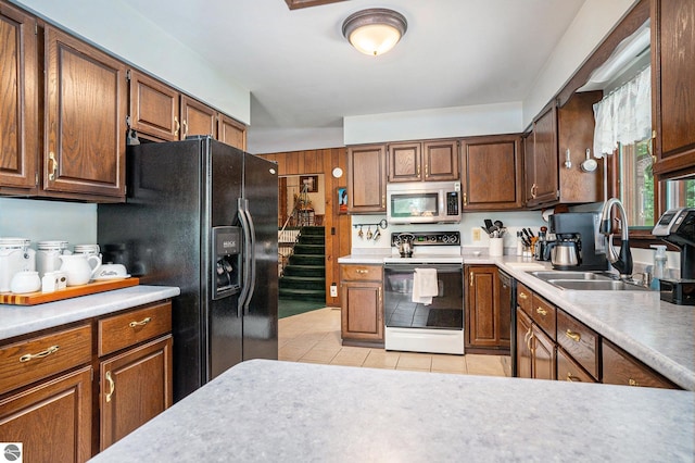 kitchen featuring black appliances, light tile patterned flooring, light countertops, and a sink