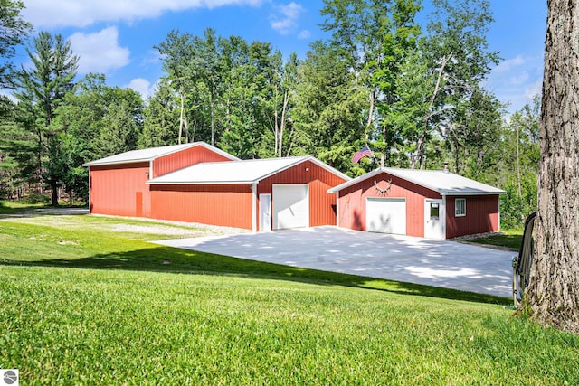 view of front facade featuring an outdoor structure, a detached garage, a pole building, and a front yard