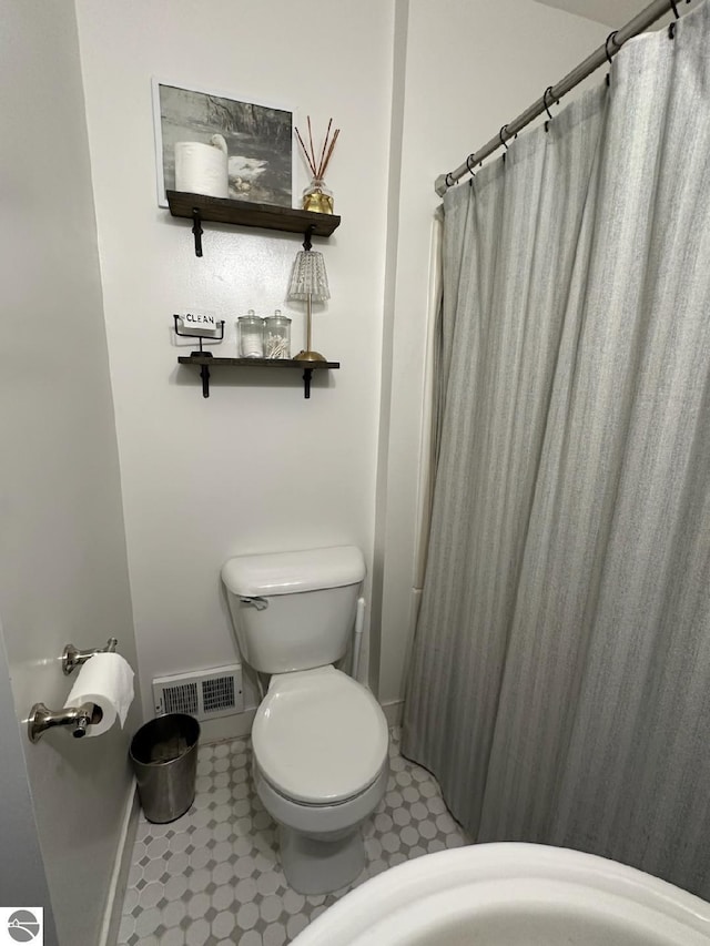 full bathroom with toilet, a shower with curtain, visible vents, and baseboards