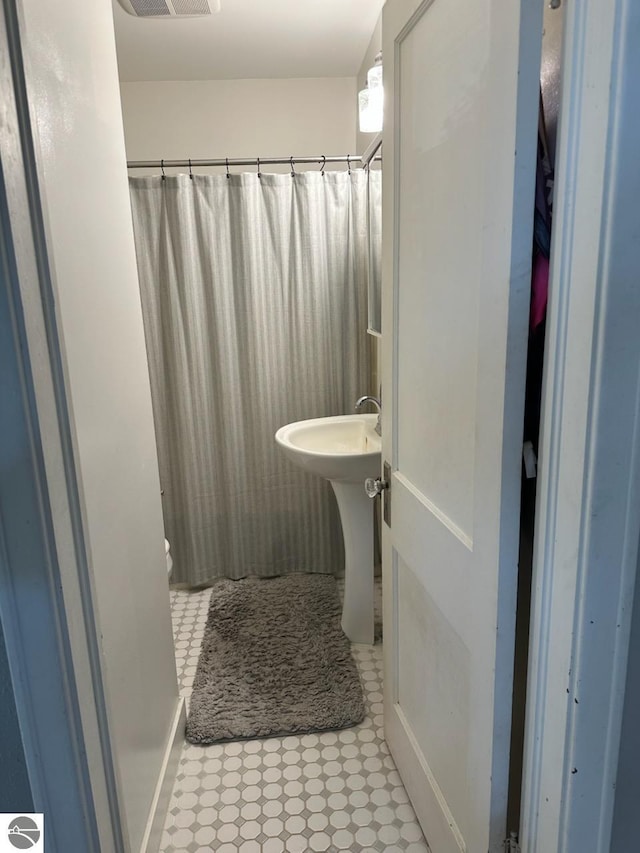 full bathroom with visible vents, a shower with shower curtain, tile patterned flooring, and a sink