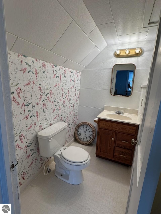 half bath featuring toilet, lofted ceiling, and vanity