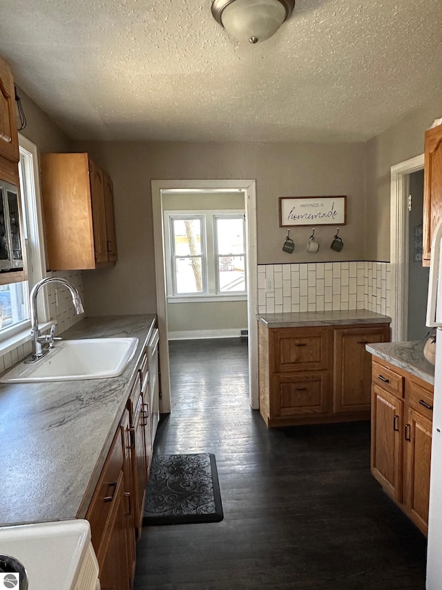 kitchen featuring range, a textured ceiling, a sink, and dark wood-type flooring