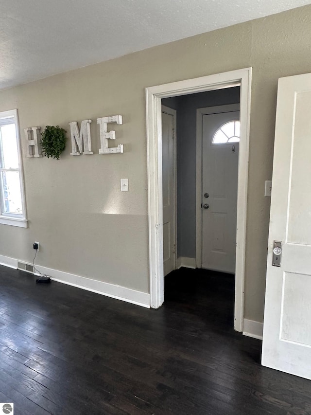 foyer entrance with dark wood-style flooring, visible vents, and baseboards