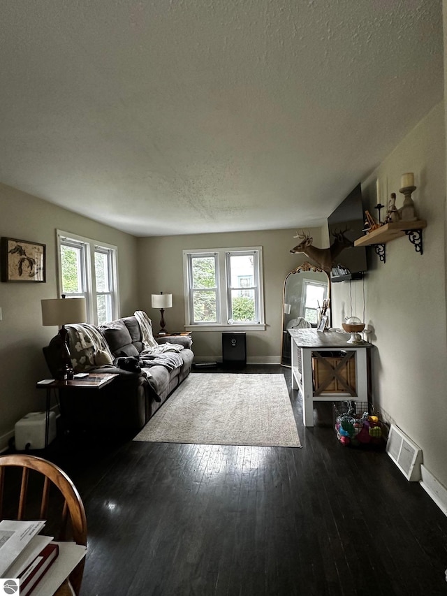 living room with dark wood finished floors, visible vents, and plenty of natural light