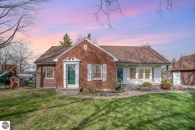 1016 Argyle Ct, Alma, MI 48801 - view of front facade with a shingled roof, brick siding, a chimney, and a front lawn