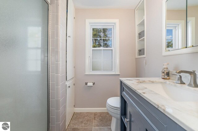 1016 Argyle Ct, Alma, MI 48801 - full bath with baseboards, toilet, tile patterned floors, a shower with shower door, and vanity