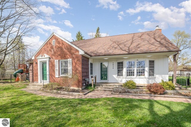 1016 Argyle Ct, Alma, MI 48801 - view of front of house featuring a front yard, brick siding, a chimney, roof with shingles, and fence