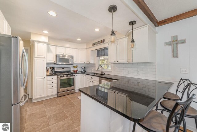 1016 Argyle Ct, Alma, MI 48801 - kitchen featuring a sink, stainless steel appliances, decorative backsplash, a peninsula, and hanging light fixtures