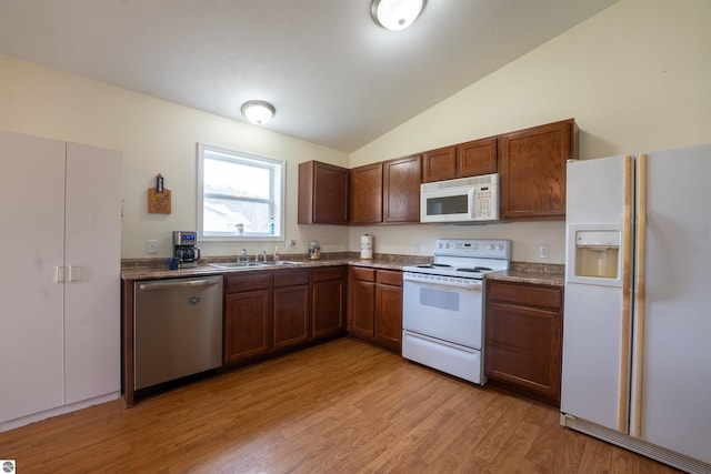 3193 Crimson Ranch Ln, Traverse City, MI 49685 - kitchen with dark countertops, white appliances, light wood-style flooring, and a sink