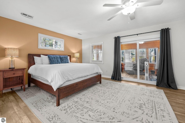 6836 NW Aarwood Trl, Rapid City, MI 49676 - bedroom featuring access to outside, visible vents, multiple windows, and wood finished floors