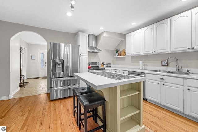 6836 NW Aarwood Trl, Rapid City, MI 49676 - kitchen featuring open shelves, wall chimney exhaust hood, arched walkways, a sink, and stainless steel appliances