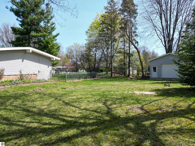 view of yard featuring fence, a detached garage, and an outbuilding