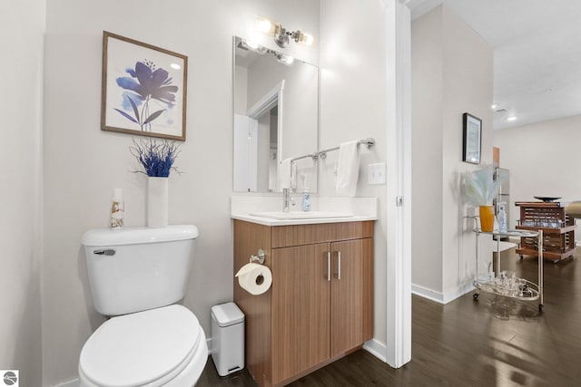 bathroom featuring toilet, baseboards, wood finished floors, and vanity