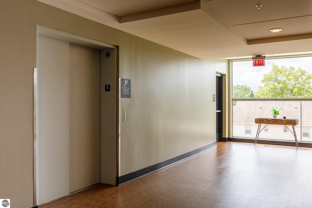 interior space with baseboards, elevator, expansive windows, and wood finished floors