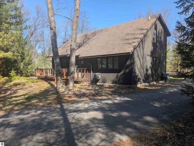 exterior space with roof with shingles and a wooden deck