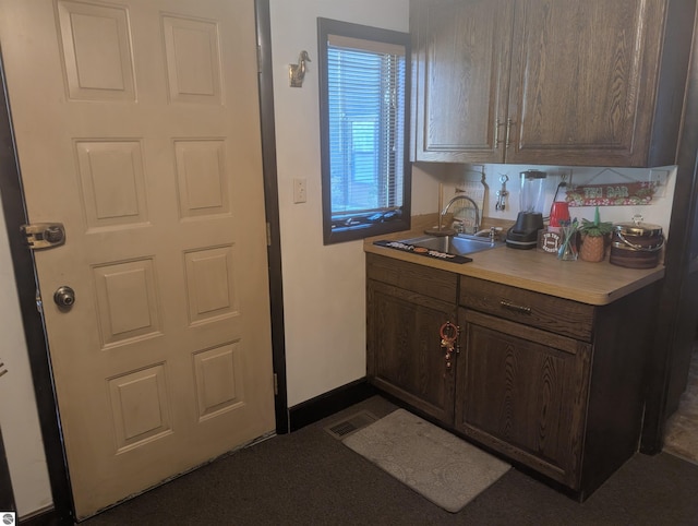 kitchen with light countertops, dark brown cabinets, visible vents, and a sink