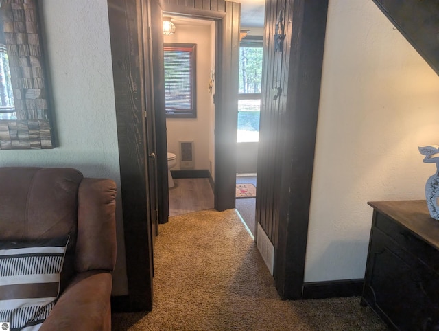 hallway with carpet floors, baseboards, and a textured wall