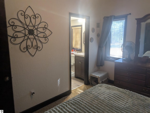 bedroom with connected bathroom and baseboards