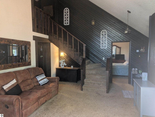 living area with carpet, high vaulted ceiling, and stairway