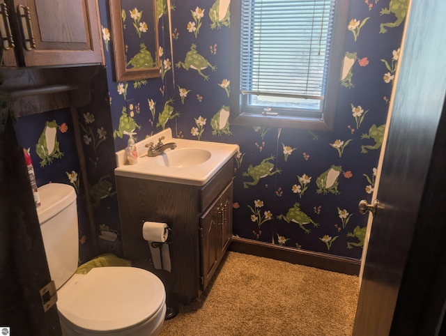 half bathroom featuring toilet, baseboards, and vanity