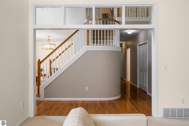 interior space with visible vents, baseboards, wood finished floors, and a notable chandelier