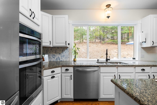 kitchen featuring a sink, dark stone countertops, appliances with stainless steel finishes, and white cabinets