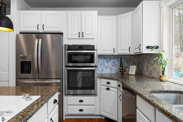 kitchen with plenty of natural light, dark stone counters, white cabinets, and stainless steel appliances